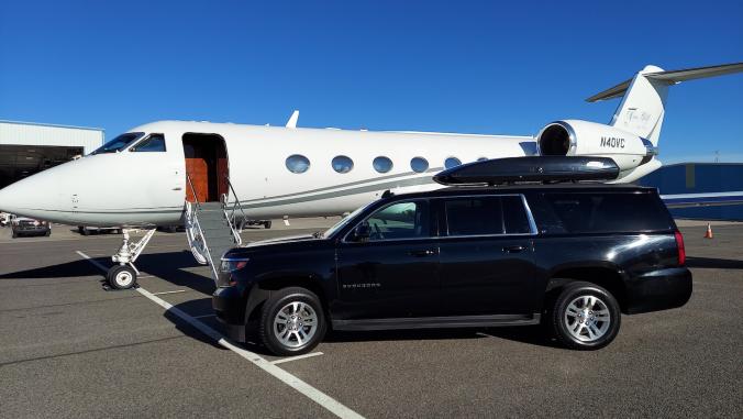 A black SUV parked by a private jet